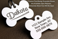 Two bone-shaped pet tags with engraved text on a brown background