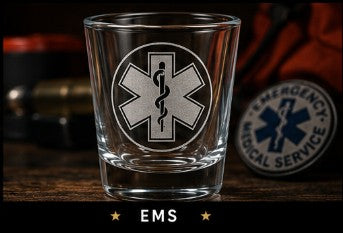 Clear glass shot glass with EMS symbol on a wooden surface