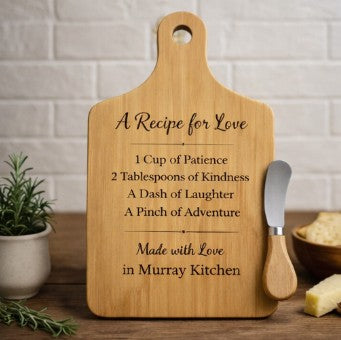 Wooden cutting board with engraved text and a knife on a kitchen counter.